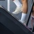 Strong sporty woman in white sportswear warm up training running on a treadmill climber stairs machine in gym indoors.